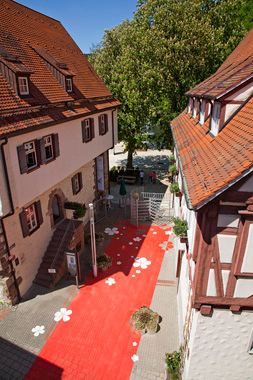 Ein roter Teppich mit Blüten der Plumeria bedeckt die Badgasse Lutz & Buss Architekten AG